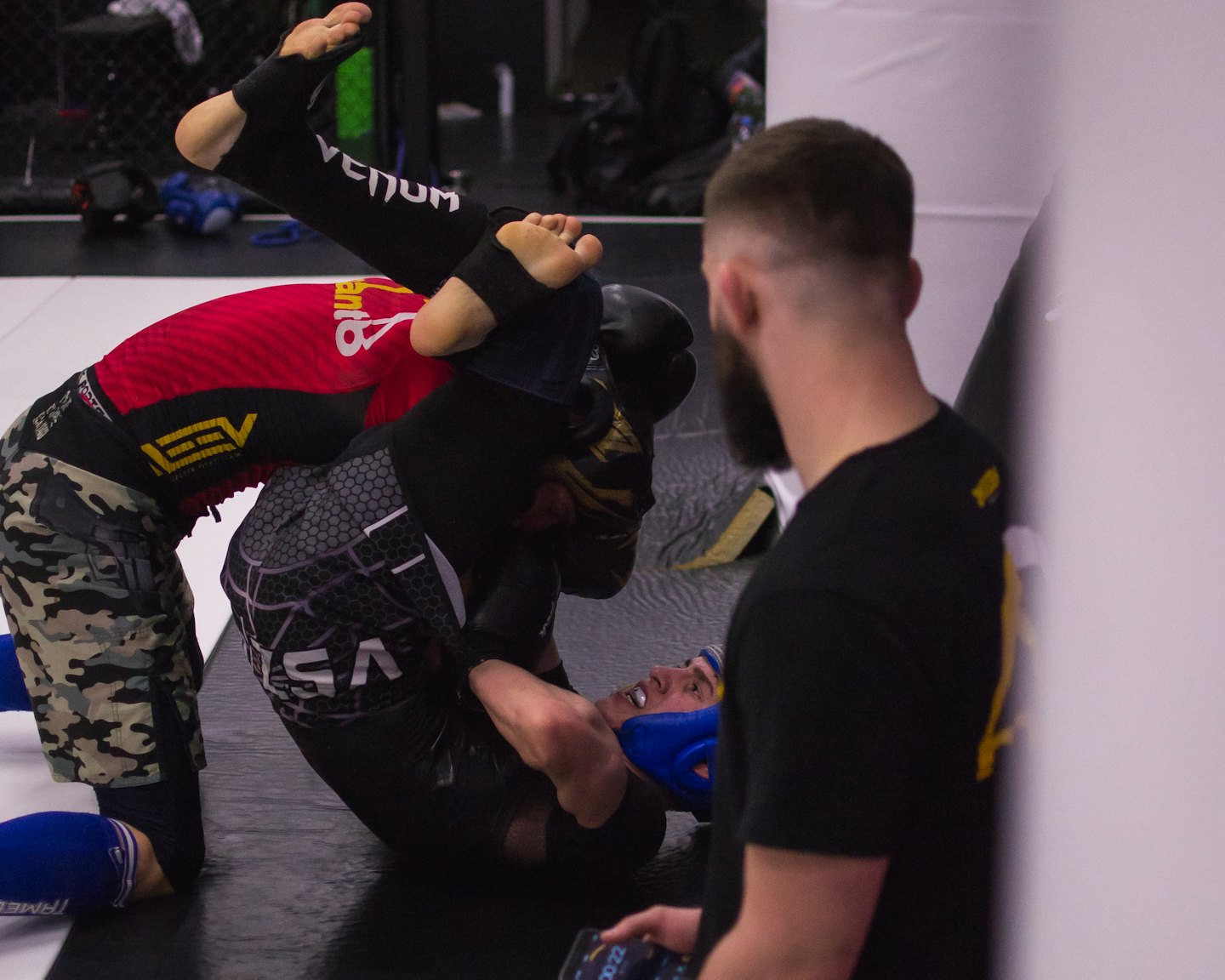 Hombre con barba entrenando artes marciales mixtas en un tapete de gimnasio.